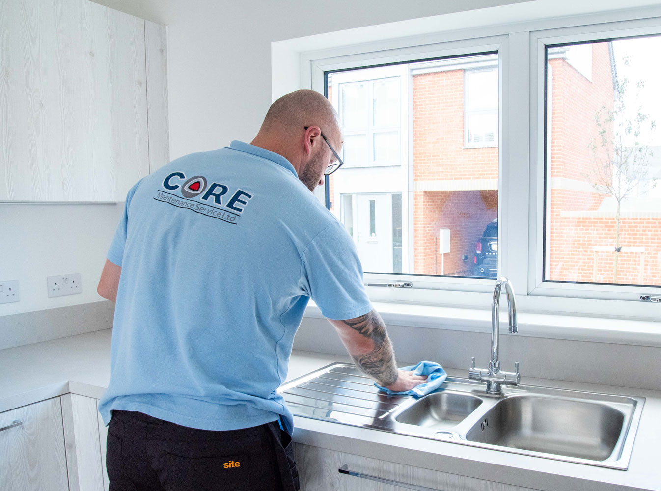 Man wearing pale blue shirt with Core logo polishing sink.